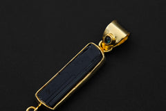 Close-up of layered gold-plated pendant showing Blue Moonstone top stone, Raw Tourmaline centre, and vertical gemstone setting.