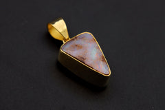 Lightning Ridge White Opal pendant shown on a dark background with 18k gold-plated sterling silver and freeform opal face.