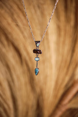 Opal Dravite Aquamarine Turquoise pendant shown on natural texture, with blue and earthy stones in oxidized sterling silver.