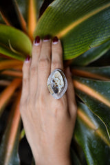 Ancient Spiral Ammonite ring shown worn on the hand, with hammered sterling silver and mixed-metal fossil setting.