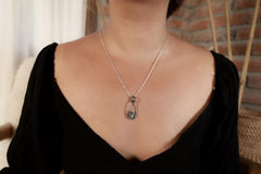 Labradorite sterling silver pendant shown worn on a model, with small celestial design and black woven cotton cord.