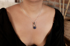 Lapis Lazuli Cosmic Ray pendant shown worn on a model, with polished sterling silver setting and black woven cotton cord.