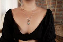 Royston Turquoise Cosmic Ray pendant shown worn on a model, with oxidized sterling silver setting and black woven cotton cord.