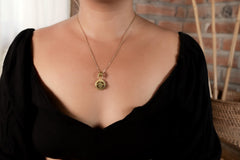 Raw Peridot pendant shown worn on a necklace, with 18k gold-plated claw frame and compact green gemstone shape.
