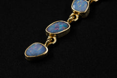 Close-up of Australian Opal droplet pendant showing blue-green play of colour, gold-plated links, and flowing cascade design.