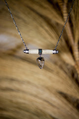 Aquamarine Bone Black Rutile Quartz pendant shown on natural texture, with blue stones, bone centrepiece, and oxidized silver setting.