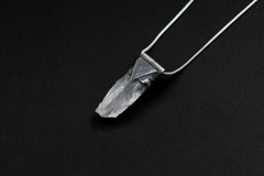 Water Clear Nepalese Inclusion Quartz Pendant shown on black background with black cotton necklace and raw clear Quartz point.