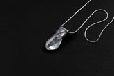 Water Clear Nepalese Inclusion Quartz Pendant shown on black background with oxidized sterling silver cap and black cotton necklace.