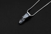 Water Clear Nepalese Inclusion Quartz pendant shown on black background with oxidized sterling silver cap and black cotton necklace.
