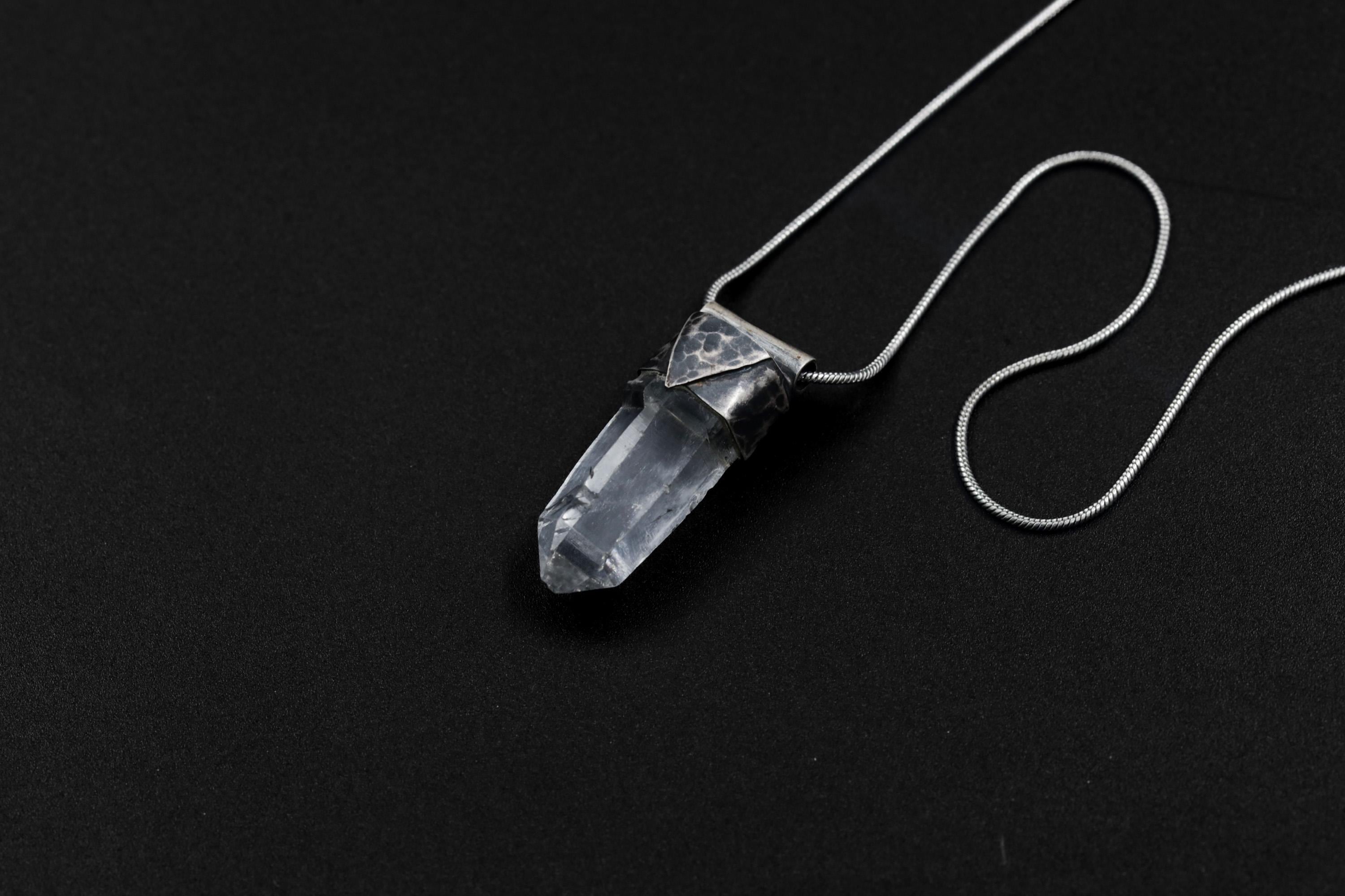 Water Clear Nepalese Inclusion Quartz pendant shown on black background with oxidized sterling silver cap and black cotton necklace.