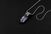 Water Clear Nepalese Inclusion Quartz pendant shown on black background with oxidized sterling silver cap and black cotton necklace.