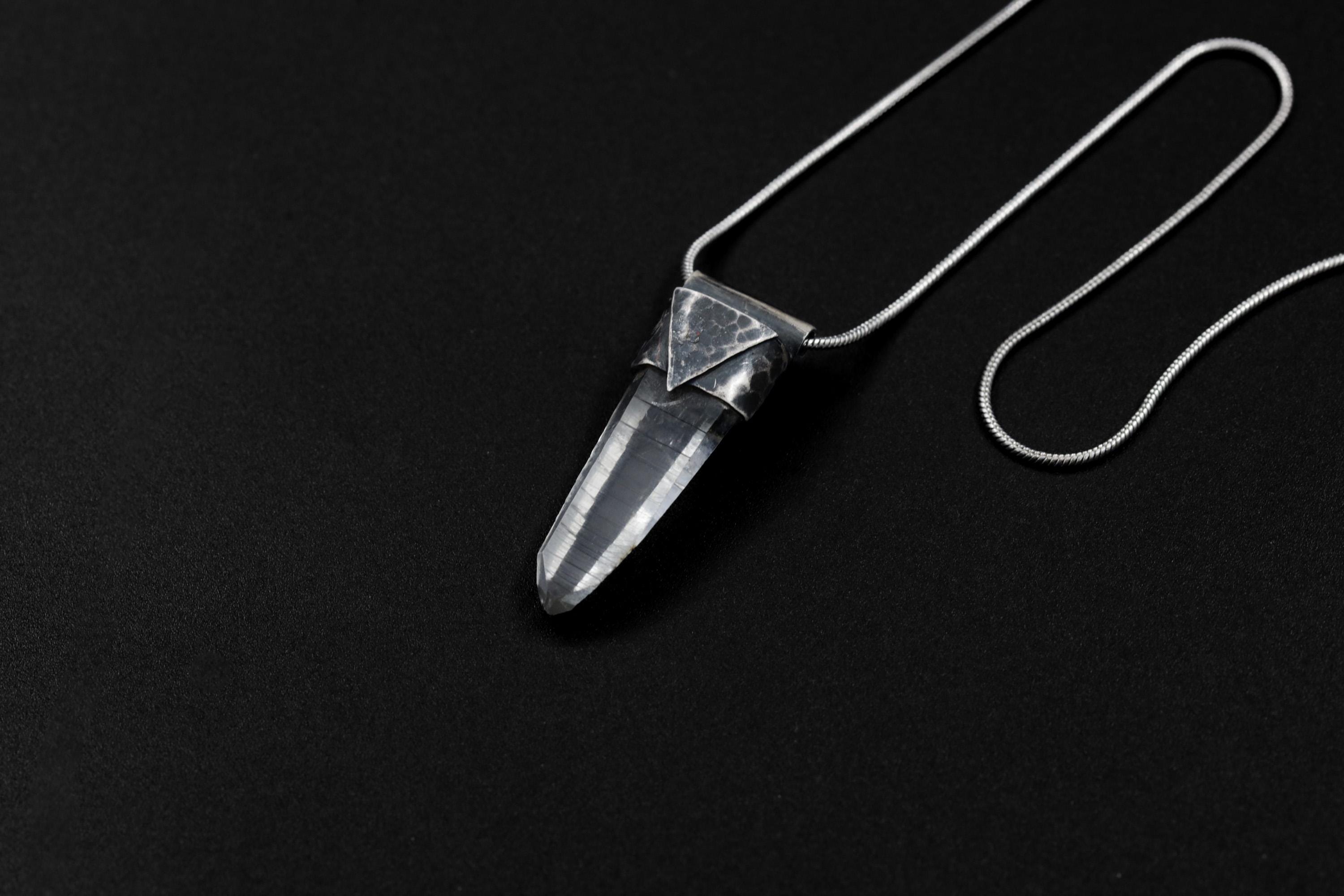 Water Clear Nepalese Inclusion Quartz Pendant shown on black background with oxidized sterling silver cap and black cotton necklace.