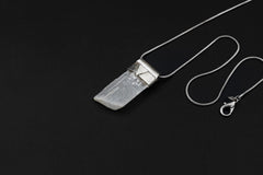 Translucent Selenite Stack Pendant shown on black background with adjustable black cotton necklace and textured silver cap.