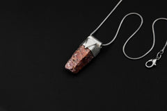 Hexagonal Ruby Stack Pendant shown on black background with adjustable black cotton necklace and sterling silver cap.