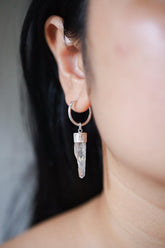 Clear Quartz single hoop earring in 925 sterling silver shown worn on the ear with raw crystal drop.
