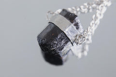 Close-up of Black Tourmaline pendant showing raw dark crystal texture and sterling silver eclipse setting.