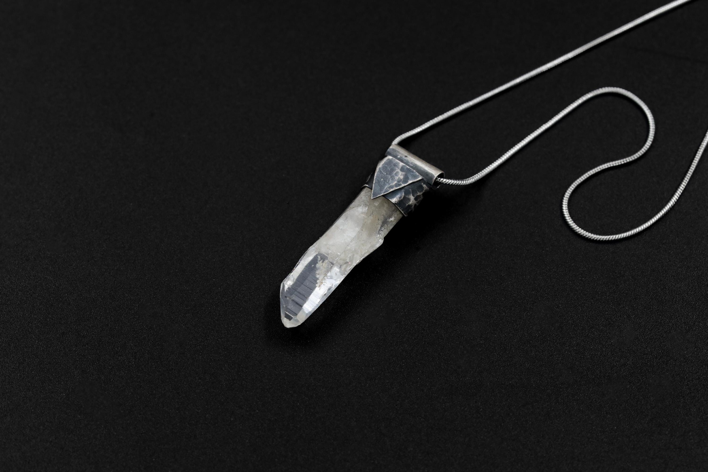Skeletal Aquamarine Stack Pendant shown on black background with sterling silver cap and raw green-blue crystal body.