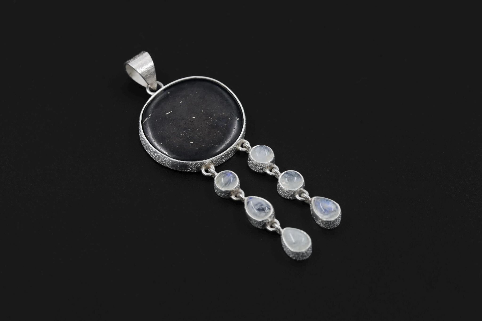Shungite Moonstone pendant on a dark background, showing high-shine sterling silver, cotton cord, and lunar dangle design.