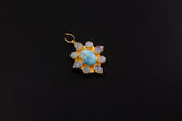Larimar and Blue Moonstone flower pendant in 18k gold-plated sterling silver, shown on a black background with luminous blue stones.