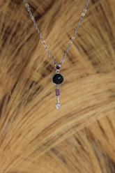 Celestial Impact Talisman shown on natural texture with Garnet, Tektite, Amethyst, Blue Moonstone, and sterling silver setting.