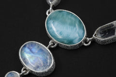 Close-up of Blue Moonstone and Larimar stones in a sterling silver necklace, showing lunar glow and ocean-blue colour.