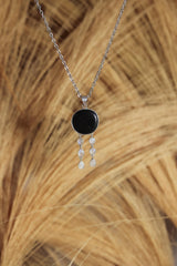 Nightseer’s Echo pendant shown on natural texture, with black Shungite centre stone and six Blue Moonstone dangles.