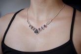 Temple of the Violet Flame necklace shown worn on the chest, with Green Tourmaline, raw Ruby, and Petroleum Quartz in sterling silver.