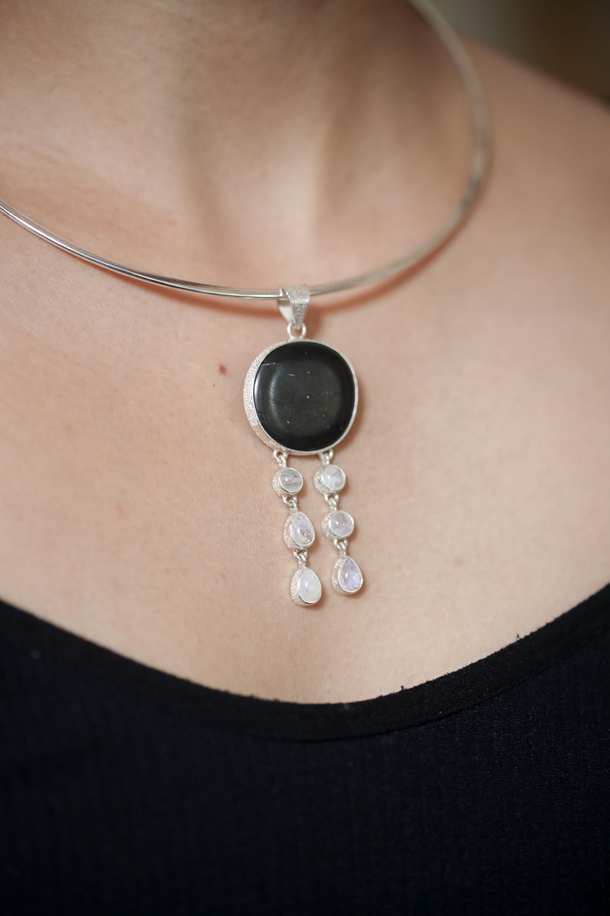 Nightseer’s Echo pendant shown worn on a model, with deep black Shungite and Blue Moonstone dangles in polished silver.