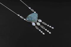 Ocean’s Whisper Radiance necklace shown on sand, with Larimar, Blue Moonstone, Clear Quartz, and sterling silver box chain.
