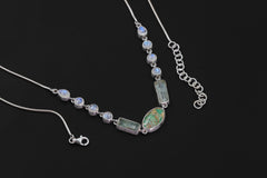 Sleeping Beauty Turquoise Aquamarine Rainbow Moonstone necklace shown on a dark background with sterling silver snake chain.