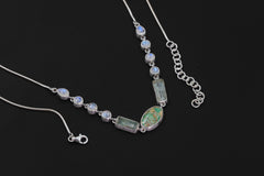 Sleeping Beauty Turquoise Aquamarine Rainbow Moonstone necklace shown on a dark background with sterling silver snake chain.