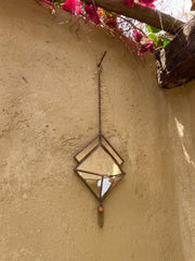 Copper and mirrored glass Quartz reliquary ornament hanging in sunlight with geometric wall decor shape.