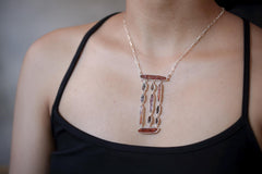 Flamepath Alignment necklace shown worn on the chest, with raw Red Kyanite, Petroleum Smoky Quartz, and sterling silver dangles.