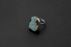 Freeform Larimar sterling silver ring shown on a dark background, with soft blue stone and polished bezel setting.