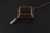 Copper Clear Quartz hanging decoration shown on dark background with geometric glass frame and raw crystal point.