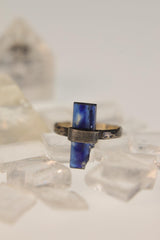 Raw Kyanite sterling silver ring displayed on clear quartz, with deep blue blade crystal and oxidized hammered band.