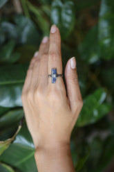 Handmade oxidized 925 sterling silver raw Kyanite ring shown worn on the hand, with deep indigo crystal and hammered band.