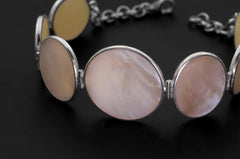 Close view of Mother of Pearl bracelet showing creamy shell cabochons and polished sterling silver bezels.