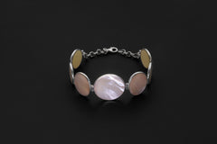 Mother of Pearl bracelet displayed on dark background with mixed round and oval shell cabochons.
