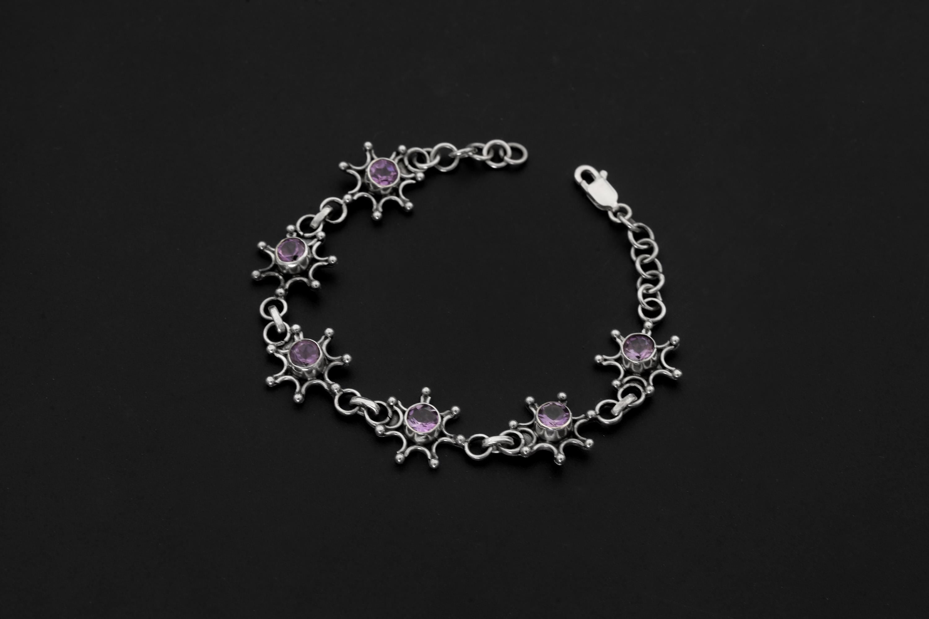 Amethyst starburst bracelet shown on dark background with polished sterling silver links and purple gemstones.
