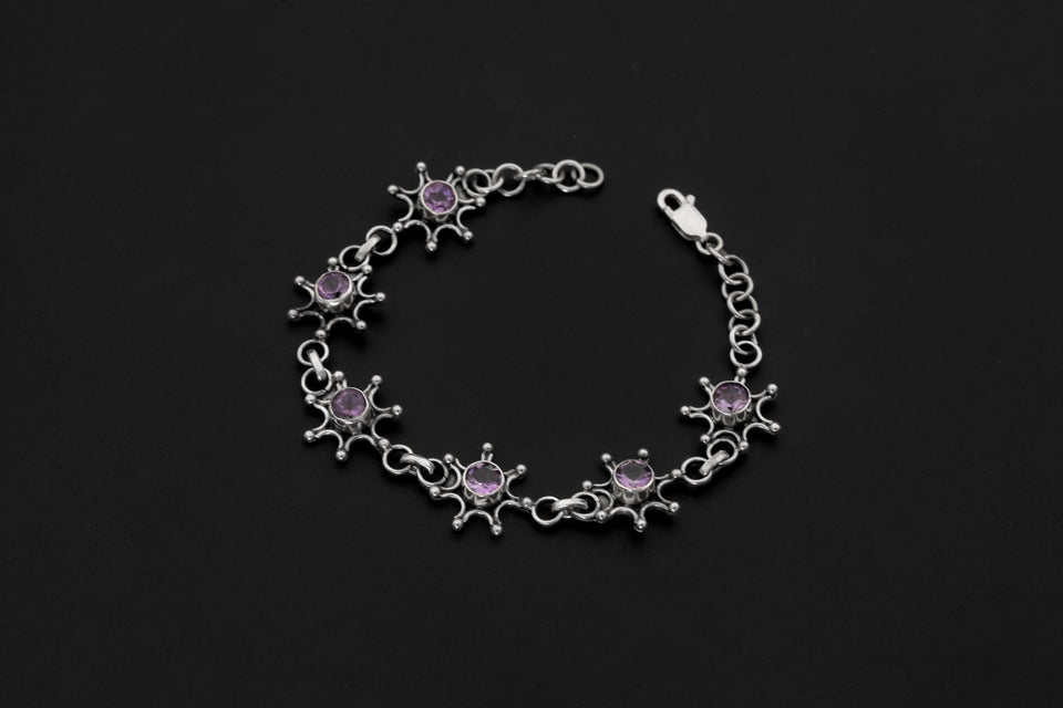 Amethyst starburst bracelet shown on dark background with polished sterling silver links and purple gemstones.