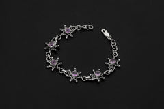 Amethyst starburst bracelet shown on dark background with polished sterling silver links and purple gemstones.
