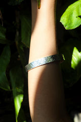 Minimalist sterling silver bangle shown worn on wrist in natural light for everyday styling.