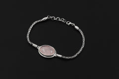 Rose Quartz bracelet displayed on dark background with oval pink cabochon and detailed sterling silver chain.