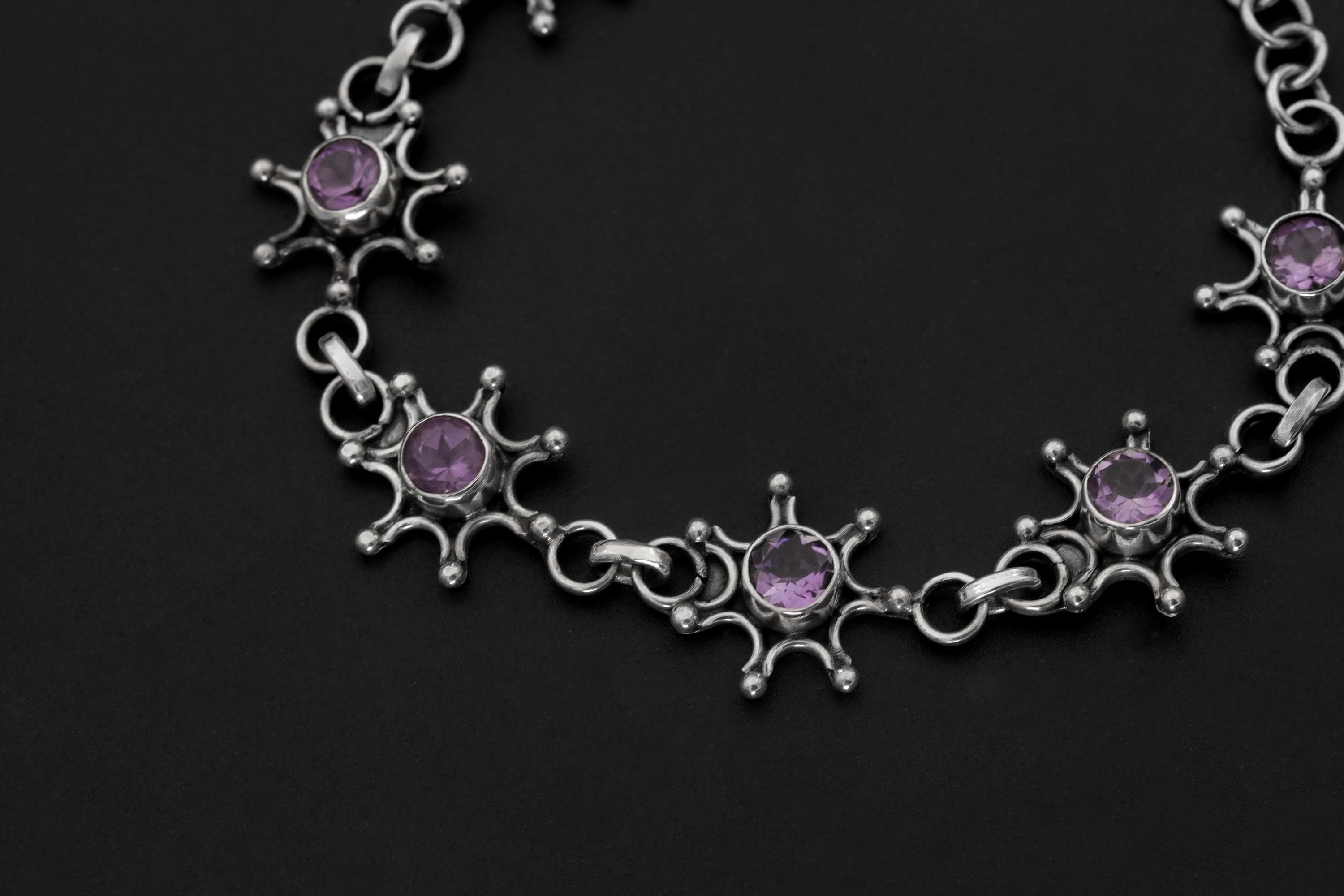 Close view of Amethyst bracelet showing violet gemstones set in detailed celestial sterling silver frames.