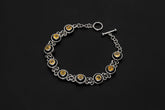 Citrine sterling silver bracelet displayed on dark background with golden faceted gemstones and toggle clasp.