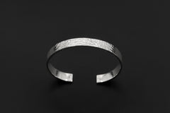Solid sterling silver bangle displayed on dark background with smooth polished circular form.