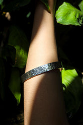 Sterling silver minimalist bangle shown worn on wrist with polished handmade finish and clean slim profile.