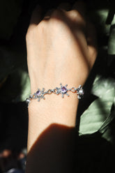 Amethyst sterling silver starburst bracelet shown worn on the wrist with violet gemstones and celestial silver settings.