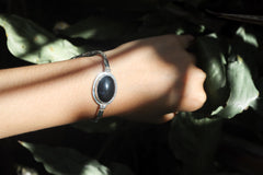 Black Onyx bracelet displayed on dark background with oval cabochon and detailed sterling silver chain.